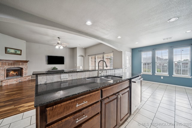 4770 S 204th E Ave, Broken Arrow, OK 74014 - kitchen with stainless steel dishwasher, light tile patterned floors, open floor plan, dark stone countertops, and a brick fireplace