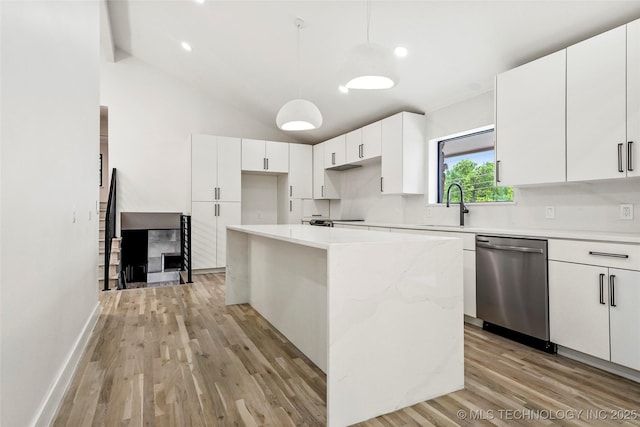 2936 E 75th St, Tulsa, OK 74136 - kitchen featuring stainless steel dishwasher, a center island, light wood-style flooring, vaulted ceiling, and white cabinetry