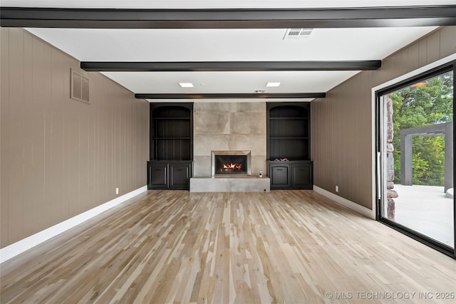 2936 E 75th St, Tulsa, OK 74136 - unfurnished living room with light wood finished floors, beamed ceiling, a fireplace, and wooden walls