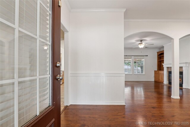 2110 S Javine Ct, Skiatook, OK 74070 - entryway featuring a ceiling fan, wood finished floors, arched walkways, a glass covered fireplace, and ornamental molding