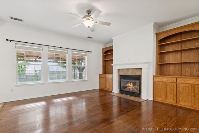 2110 S Javine Ct, Skiatook, OK 74070 - unfurnished living room featuring crown molding, a ceiling fan, a tiled fireplace, and wood finished floors