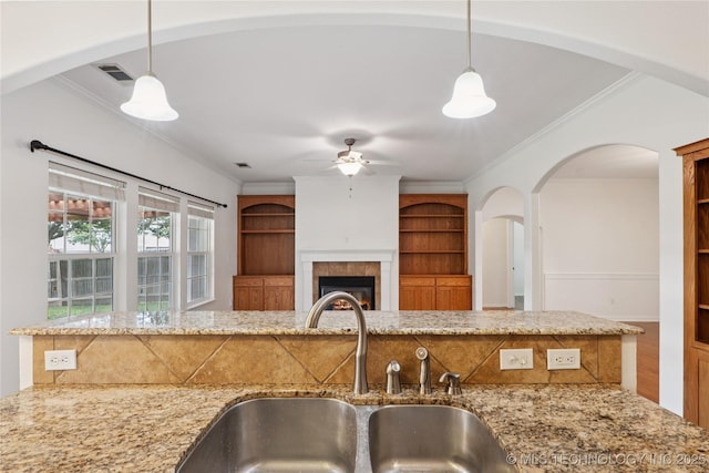 2110 S Javine Ct, Skiatook, OK 74070 - kitchen with ceiling fan, crown molding, light stone countertops, pendant lighting, and arched walkways