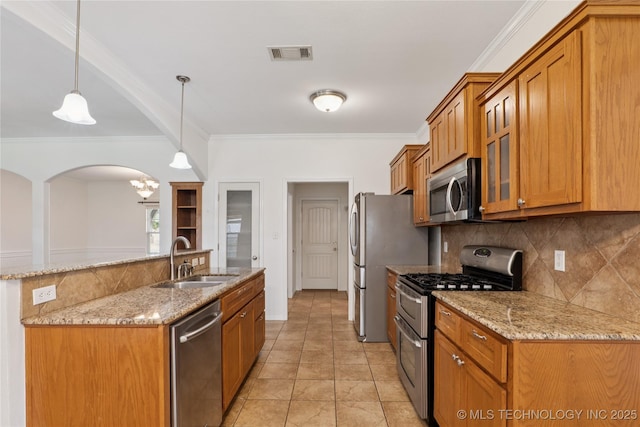 2110 S Javine Ct, Skiatook, OK 74070 - kitchen featuring appliances with stainless steel finishes, brown cabinetry, tasteful backsplash, ornamental molding, and arched walkways