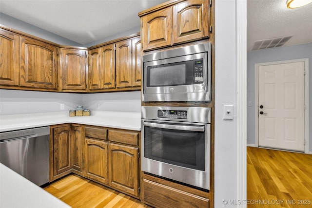7416 S 109th E Ave, Tulsa, OK 74133 - kitchen featuring appliances with stainless steel finishes, brown cabinets, light wood-style floors, and light countertops