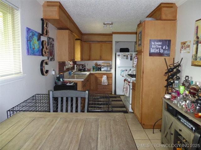 2414 S 126th E Ave, Tulsa, OK 74129 - kitchen featuring white appliances, light countertops, light tile patterned floors, brown cabinetry, and a textured ceiling
