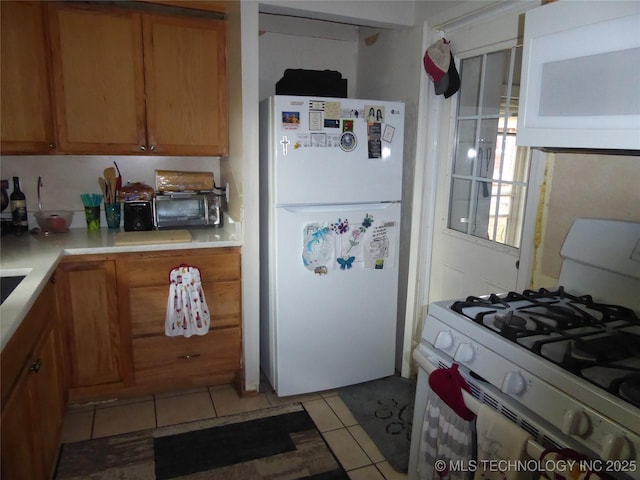 2414 S 126th E Ave, Tulsa, OK 74129 - kitchen featuring white appliances, light tile patterned floors, brown cabinetry, and light countertops
