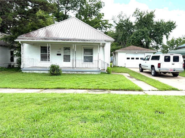 903 W Broadway St, Henryetta, OK 74437 - view of front of home with a garage, covered porch, driveway, an outbuilding, and a metal roof