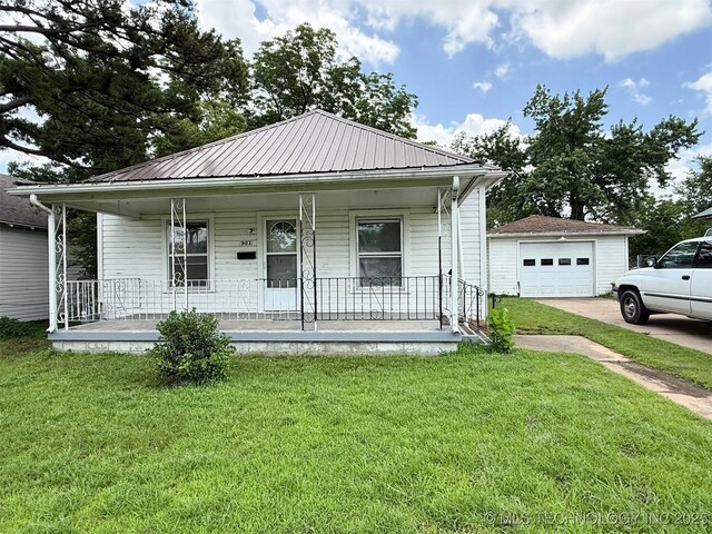 903 W Broadway St, Henryetta, OK 74437 - view of front of house featuring a porch, driveway, a detached garage, and a front lawn