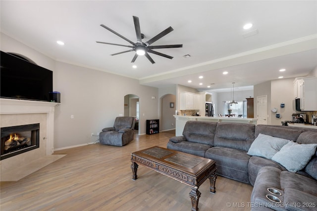 14220 S Vandalia Ave, Bixby, OK 74008 - living room with a ceiling fan, arched walkways, light wood finished floors, a fireplace, and recessed lighting