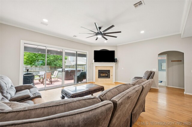 14220 S Vandalia Ave, Bixby, OK 74008 - living area featuring a ceiling fan, arched walkways, a fireplace with flush hearth, light wood-style flooring, and crown molding