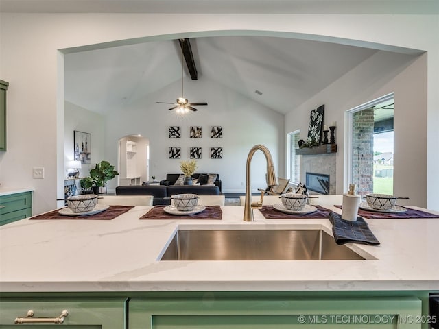27742 E 109th St S, Coweta, OK 74429 - kitchen featuring green cabinets, open floor plan, beamed ceiling, arched walkways, and light stone countertops
