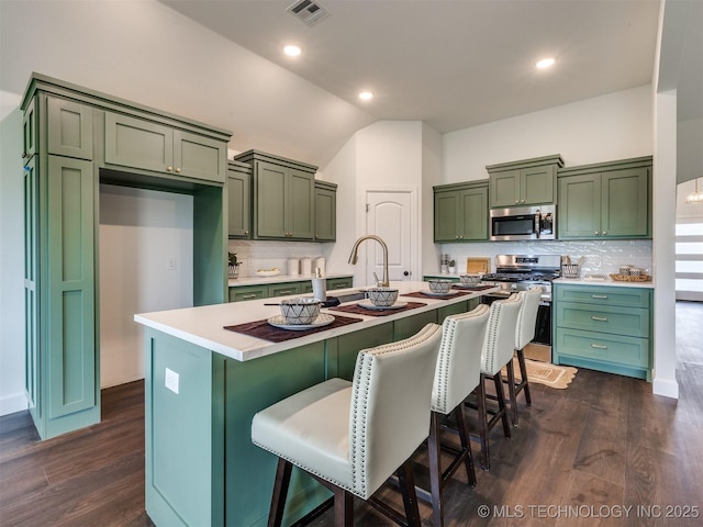27742 E 109th St S, Coweta, OK 74429 - kitchen with stainless steel appliances, green cabinets, vaulted ceiling, tasteful backsplash, and a kitchen island with sink