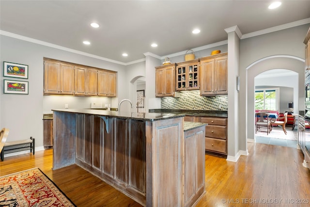 243 E 27th Pl, Tulsa, OK 74114 - kitchen with arched walkways, an island with sink, light wood-type flooring, recessed lighting, and ornamental molding