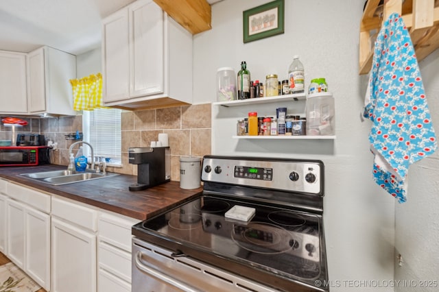 705 S E St, Skiatook, OK 74070 - kitchen featuring stainless steel range with electric stovetop, backsplash, white cabinetry, and butcher block countertops