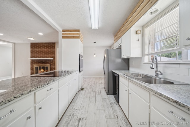 148 E 57th St, Tulsa, OK 74105 - kitchen with a textured ceiling, black appliances, white cabinets, tasteful backsplash, and light wood finished floors