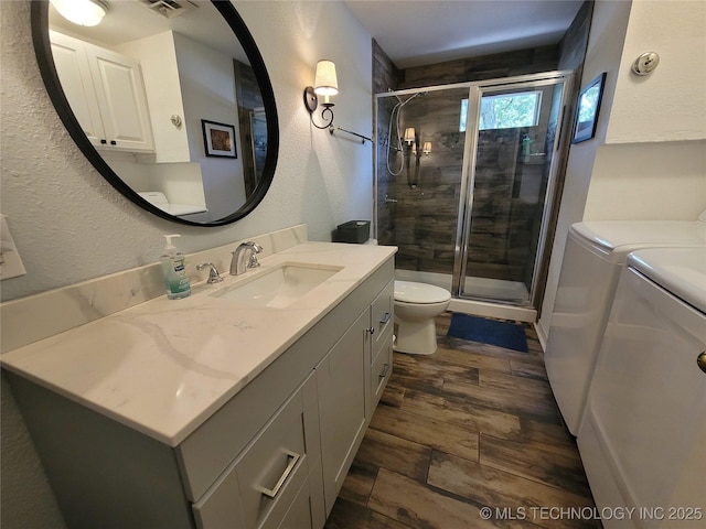 1416 Robin Hood Rd, Eufaula, OK 74432 - full bathroom with washing machine and dryer, vanity, a shower stall, wood finished floors, and a textured wall