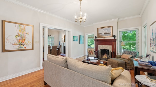 429 Kendall, Muskogee, OK 74401 - living room featuring a chandelier, light wood-style flooring, ornamental molding, a warm lit fireplace, and ornate columns