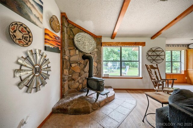 1001 E 1990th Rd, Soper, OK 74759 - living room with a textured ceiling, beam ceiling, a wood stove, and wood finished floors