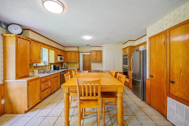 1001 E 1990th Rd, Soper, OK 74759 - kitchen featuring appliances with stainless steel finishes, wallpapered walls, light countertops, a textured ceiling, and brown cabinetry