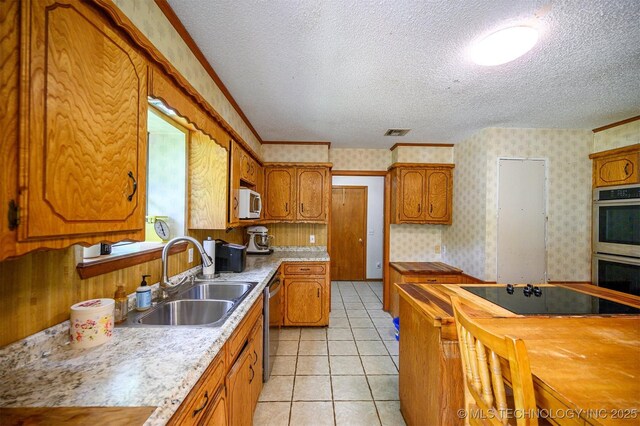 1001 E 1990th Rd, Soper, OK 74759 - kitchen with stainless steel appliances, wallpapered walls, a textured ceiling, brown cabinets, and light tile patterned floors