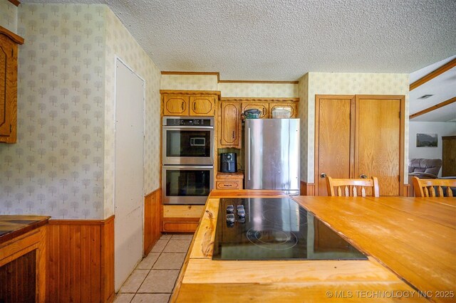 1001 E 1990th Rd, Soper, OK 74759 - kitchen with appliances with stainless steel finishes, wallpapered walls, a textured ceiling, brown cabinets, and butcher block countertops