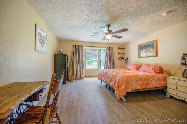 1001 E 1990th Rd, Soper, OK 74759 - bedroom with wood finished floors, a textured ceiling, and ceiling fan