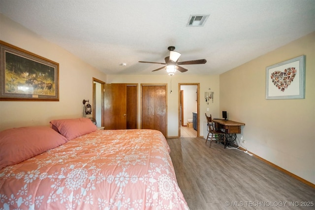 1001 E 1990th Rd, Soper, OK 74759 - bedroom with two closets, wood finished floors, ensuite bath, and ceiling fan
