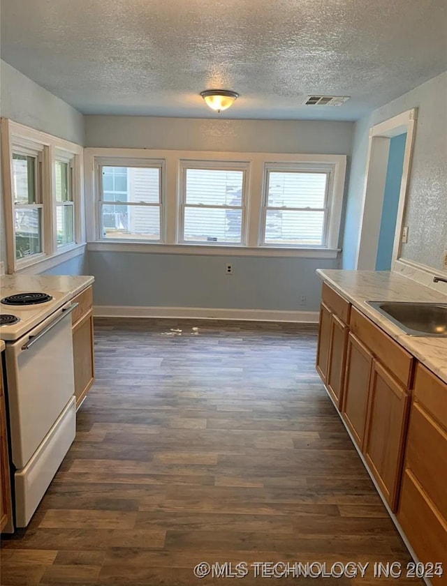 210 N G St, Muskogee, OK 74403 - kitchen with white range with electric stovetop, a textured ceiling, dark wood-style flooring, brown cabinets, and light countertops