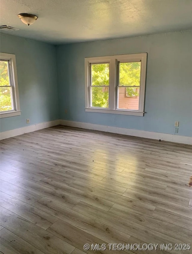 210 N G St, Muskogee, OK 74403 - spare room featuring healthy amount of natural light, wood finished floors, and a textured ceiling