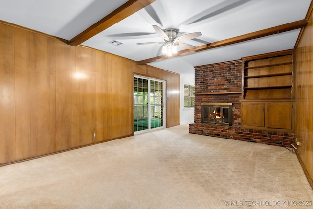 6725 E 51st Pl S, Tulsa, OK 74145 - unfurnished living room featuring beam ceiling, wood walls, carpet, a ceiling fan, and a brick fireplace