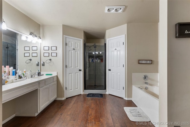 704 NE 3rd St, Wagoner, OK 74467 - full bath featuring vanity, a shower stall, a garden tub, and wood finished floors