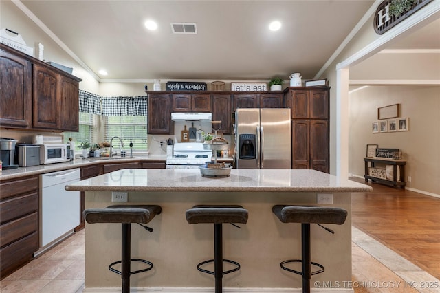 704 NE 3rd St, Wagoner, OK 74467 - kitchen featuring white appliances, under cabinet range hood, a kitchen bar, a center island, and crown molding