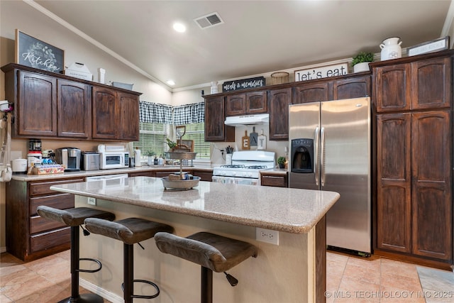704 NE 3rd St, Wagoner, OK 74467 - kitchen featuring stainless steel fridge, white range with gas cooktop, under cabinet range hood, vaulted ceiling, and a breakfast bar