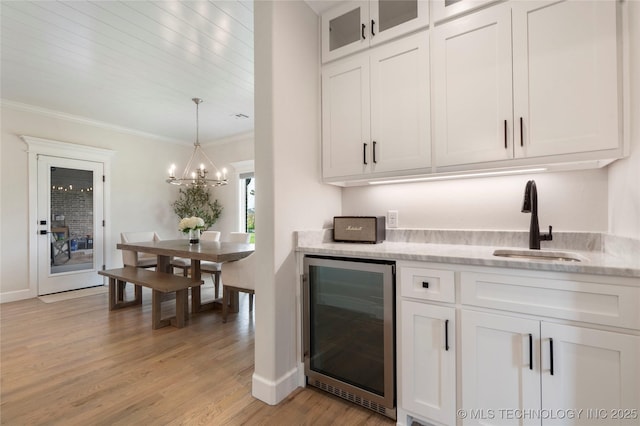 17831 S 46th E Ave, Bixby, OK 74008 - bar area featuring wine cooler, a chandelier, light wood finished floors, crown molding, and decorative light fixtures