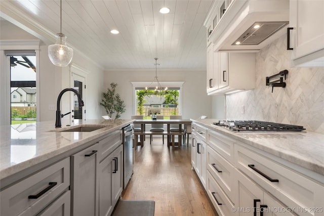 17831 S 46th E Ave, Bixby, OK 74008 - kitchen featuring custom range hood, light wood-style floors, appliances with stainless steel finishes, tasteful backsplash, and decorative light fixtures