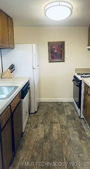 410 W 7th St Unit 229, Tulsa, OK 74119 - kitchen featuring dark wood-style floors, stainless steel dishwasher, range with gas cooktop, light countertops, and dark brown cabinets
