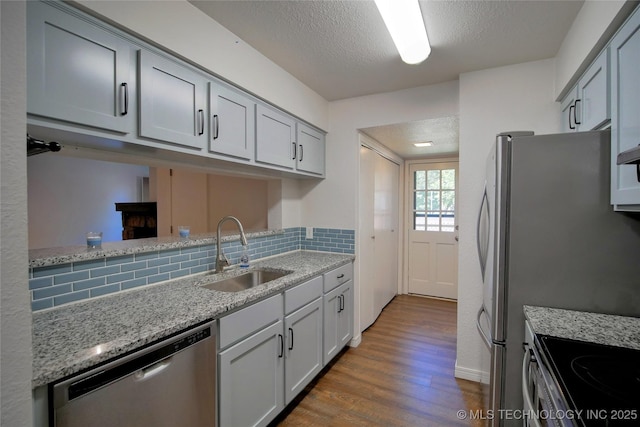 6370 S 80th E Ave Unit E, Tulsa, OK 74133 - kitchen featuring stainless steel appliances, dark wood-style flooring, tasteful backsplash, a textured ceiling, and light stone counters
