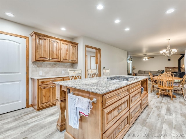 30833 S 4190th Rd, Inola, OK 74006 - kitchen with stainless steel gas stovetop, light wood-type flooring, decorative backsplash, light stone countertops, and a ceiling fan
