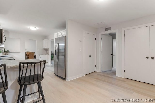 17069 S 87th Ave E, Bixby, OK 74008 - kitchen featuring stainless steel fridge, light wood-style floors, white cabinetry, and a breakfast bar