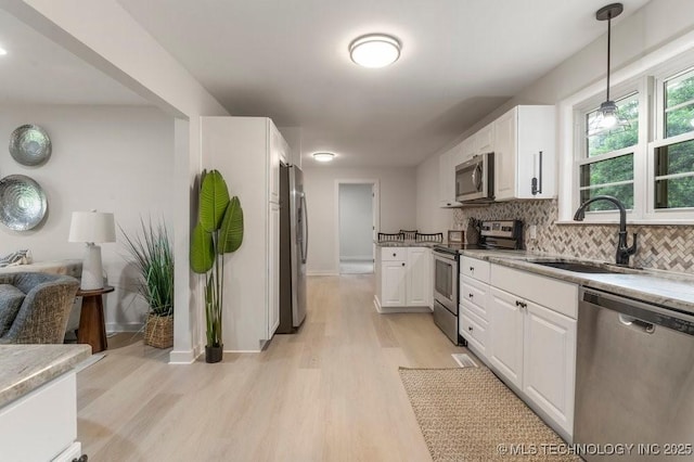 17069 S 87th Ave E, Bixby, OK 74008 - kitchen featuring appliances with stainless steel finishes, white cabinetry, light wood finished floors, backsplash, and hanging light fixtures
