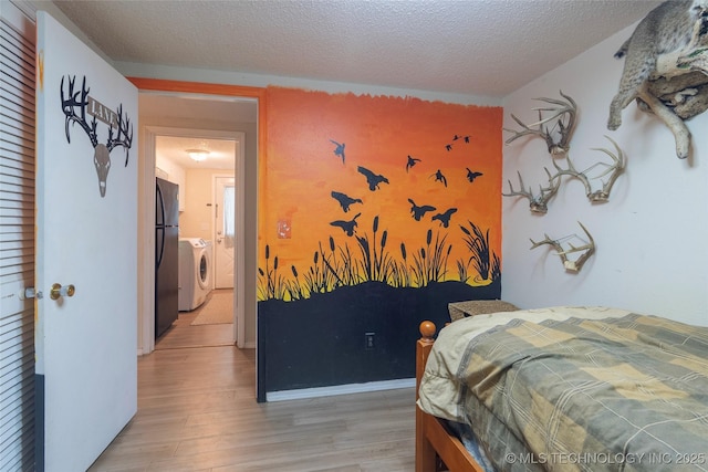 9730 S 4050th Rd, Talala, OK 74080 - bedroom featuring washer and clothes dryer, light wood-style flooring, freestanding refrigerator, and a textured ceiling