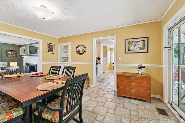 1347 E 37th St, Tulsa, OK 74105 - dining space with a textured ceiling, plenty of natural light, ornamental molding, stone tile floors, and a fireplace