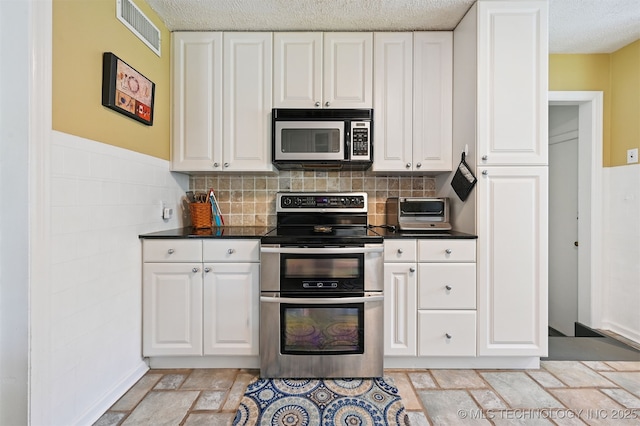1347 E 37th St, Tulsa, OK 74105 - kitchen with stainless steel appliances, stone tile flooring, white cabinets, a textured ceiling, and dark countertops