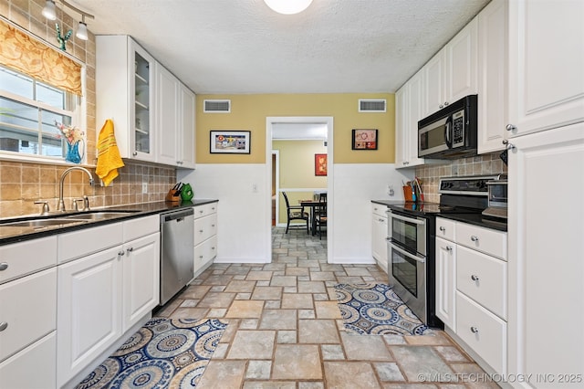 1347 E 37th St, Tulsa, OK 74105 - kitchen with appliances with stainless steel finishes, dark countertops, a textured ceiling, and white cabinets