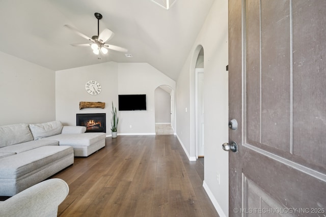 311 E 4th St, Skiatook, OK 74070 - living area featuring wood finished floors, ceiling fan, lofted ceiling, arched walkways, and a glass covered fireplace