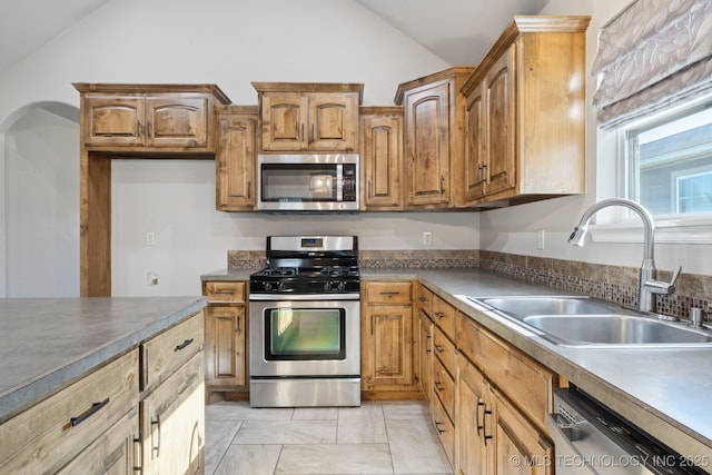 311 E 4th St, Skiatook, OK 74070 - kitchen featuring stainless steel appliances, lofted ceiling, brown cabinetry, and dark countertops