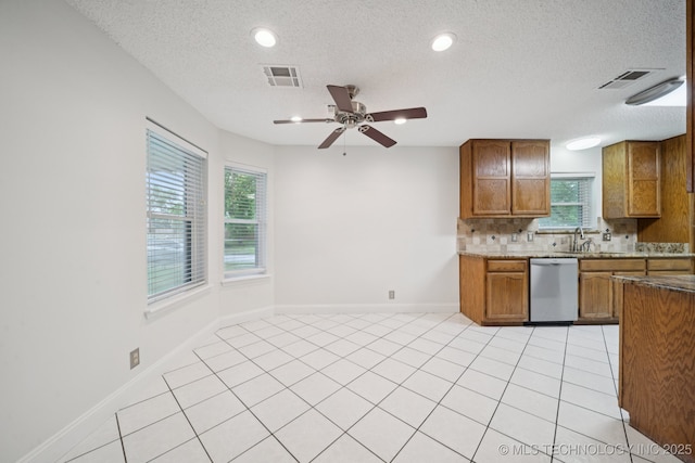13111 E 80th St N, Owasso, OK 74055 - kitchen featuring dishwasher, brown cabinets, a textured ceiling, decorative backsplash, and a ceiling fan
