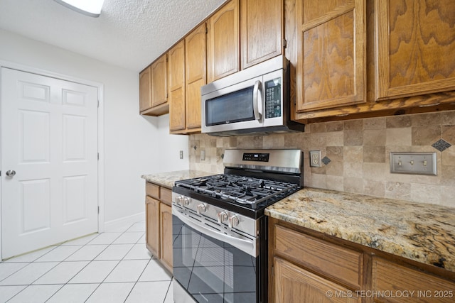 13111 E 80th St N, Owasso, OK 74055 - kitchen featuring stainless steel appliances, light tile patterned floors, light stone counters, tasteful backsplash, and a textured ceiling