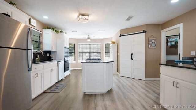 3942 Elm Dr, Kingston, OK 73439 - kitchen with freestanding refrigerator, a barn door, a center island, dishwasher, and dark countertops