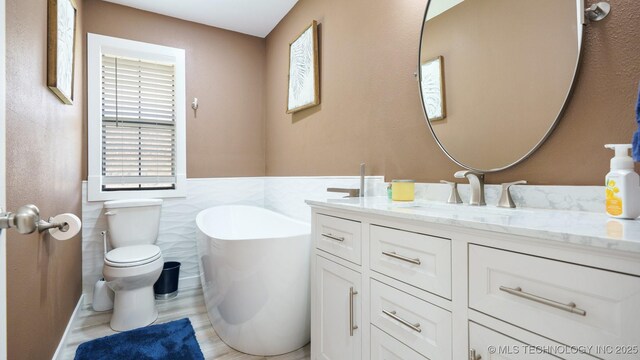 3942 Elm Dr, Kingston, OK 73439 - bathroom with vanity, a freestanding tub, tile walls, and a wainscoted wall